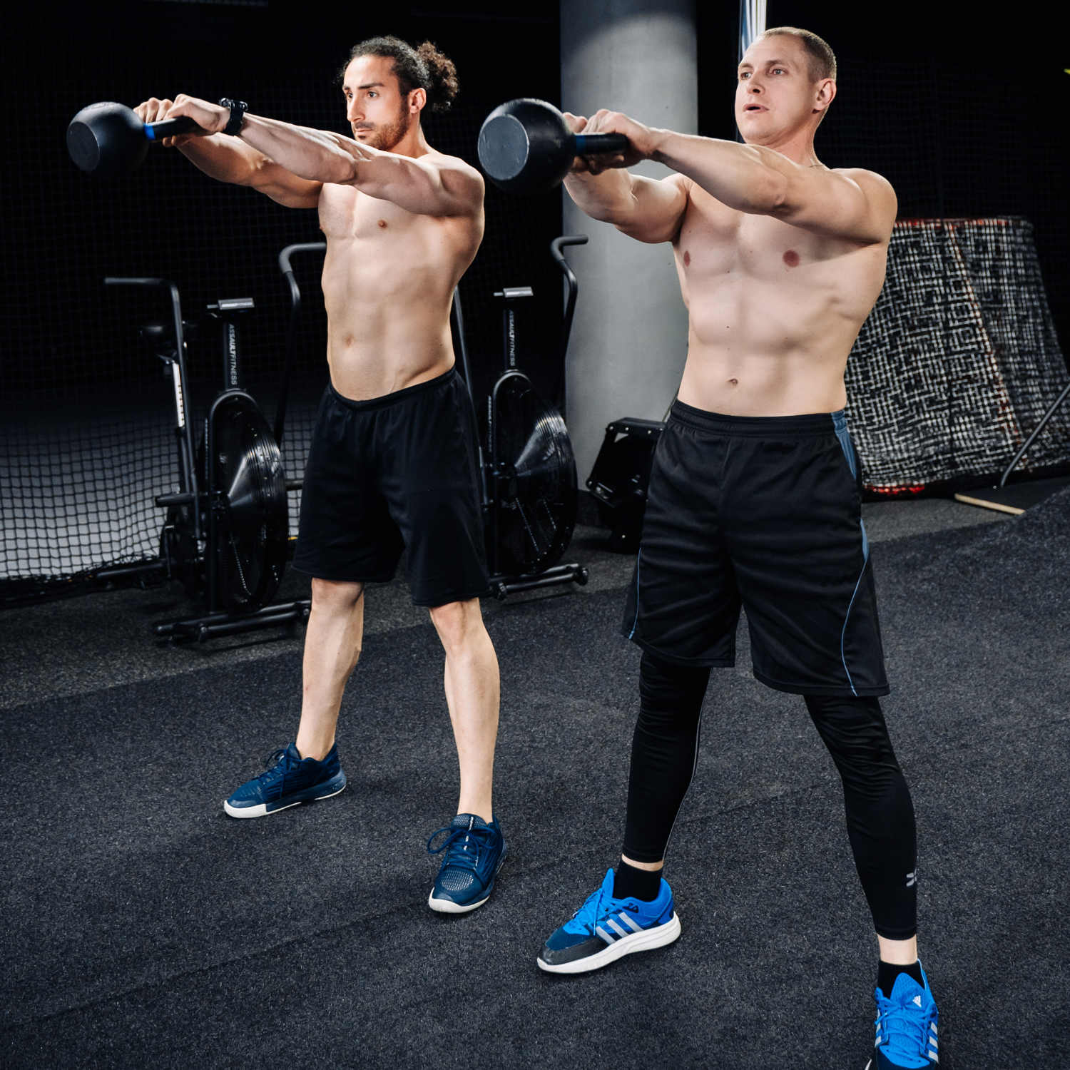 Двое мужчин в спортивной подтянутой форме тренируются с гирей